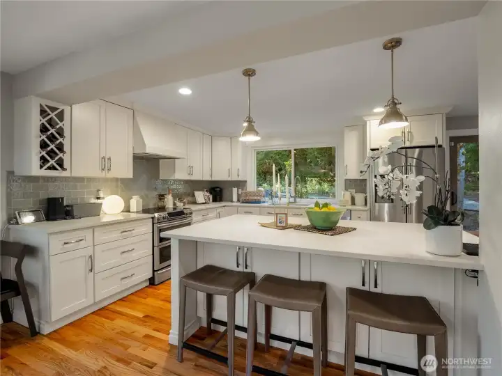 The gorgeous kitchen dazzles w/quartz countertops, white shaker cabinetry, herringbone tile backsplash, stainless steel appliances, & a large island with seating.