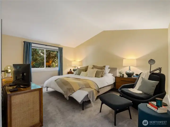 The primary suite accommodates a king-sized bed with a seating area, bedside tables, and dresser.