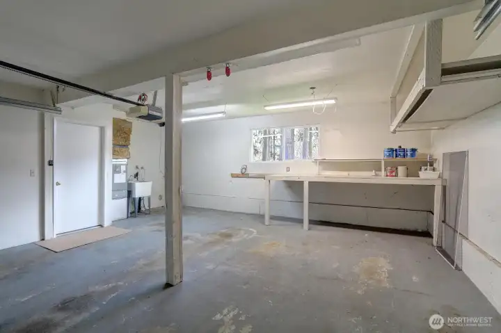 Big 440 sq ft garage. Note the laundry set up in back with adjacent utility sink.  Electric garage door opener. Upper shelving and nice workbench.
