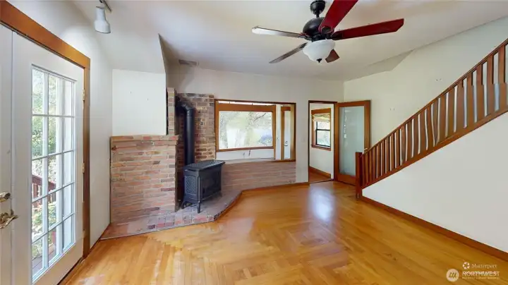 View from the kitchen of the living room with gas stove and french doors to deck.