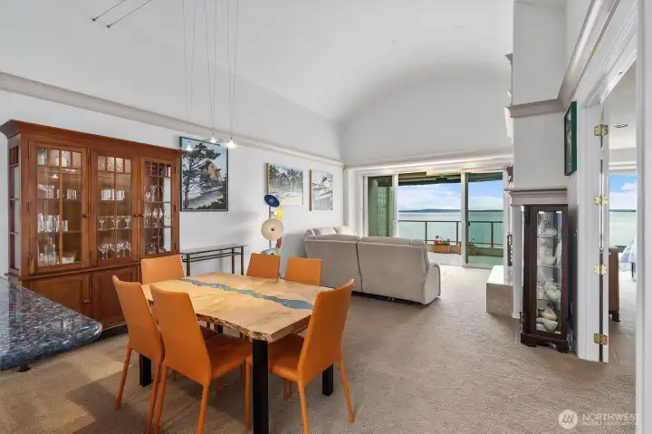This photo beautifully captures the home’s soaring vaulted ceilings, which create an airy, open feel and enhance the abundance of natural light throughout the space. To the right, you’ll find the view-facing primary suite, thoughtfully positioned to take full advantage of the stunning outlook and peaceful setting.
