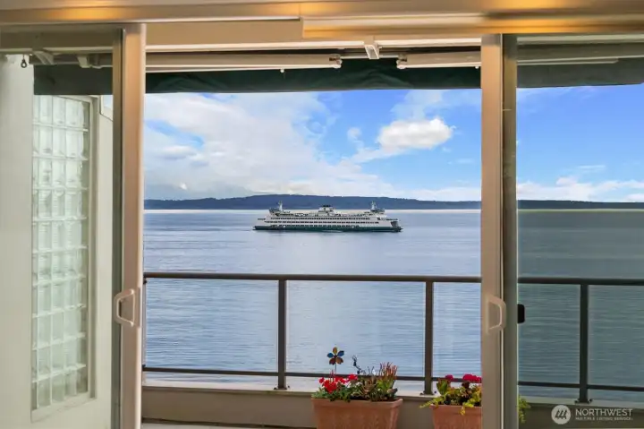 Double sliding doors extend the living room seamlessly onto the expansive view deck, creating an ideal indoor-outdoor living experience. Featuring sleek glass railings that preserve the panoramic views and a remote-controlled power awning for added comfort and shade, this inviting outdoor space is perfect for relaxing, entertaining, or enjoying sunsets year-round.