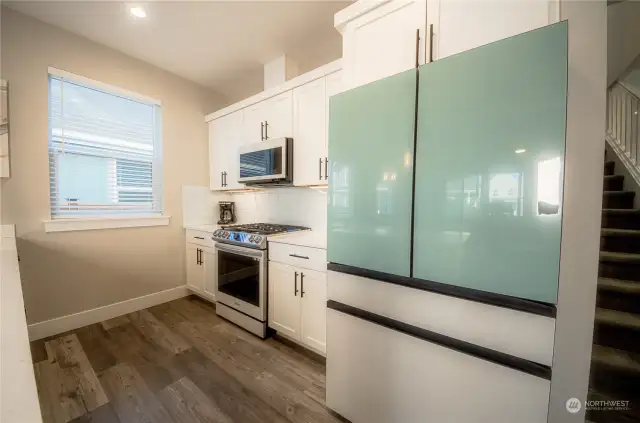 The upgraded white glass kitchen appliance package from Samsung’s Bespoke line features a French door refrigerator, propane gas stove, dishwasher and microwave. The light teal blue refrigerator doors add a coastal touch to the kitchen package.
