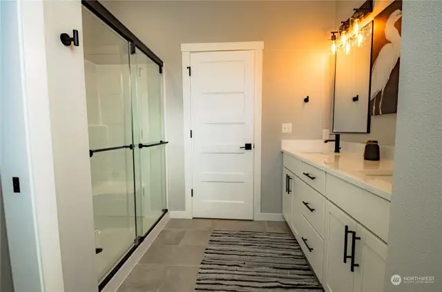 The large primary ensuite bath has a shower and is enclosed with shower doors (an upgrade) and includes an upgraded hand-held metal showerhead .