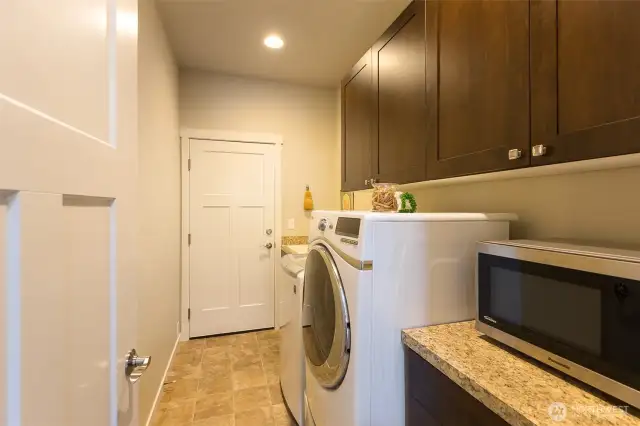 Spacious laundry room with a utility sink and plenty of cabinets. The door leads to the garage.
