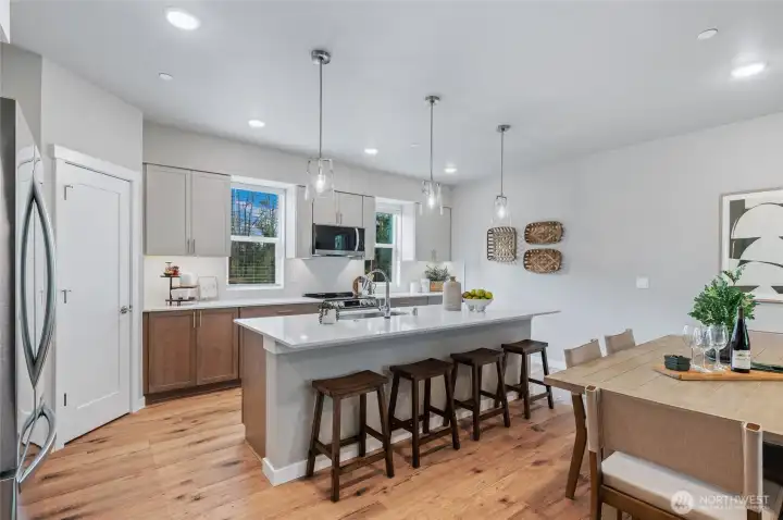 Chef's kitchen with quartz counter tops, full height kitchen backsplash, designer pendant lighting over the entertainers island. Energy efficient LG appliances included.  Photos are of model home in the community.