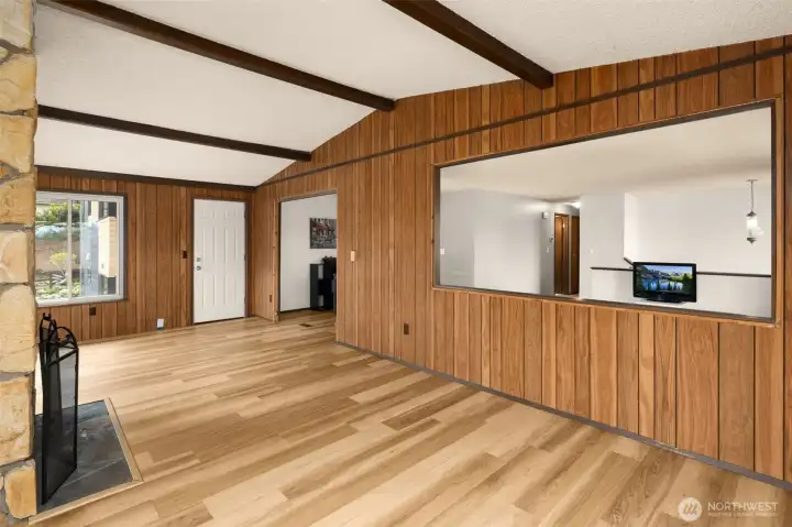 Family room with wood burning fireplace and vaulted ceilings, looks onto living room and dining area.