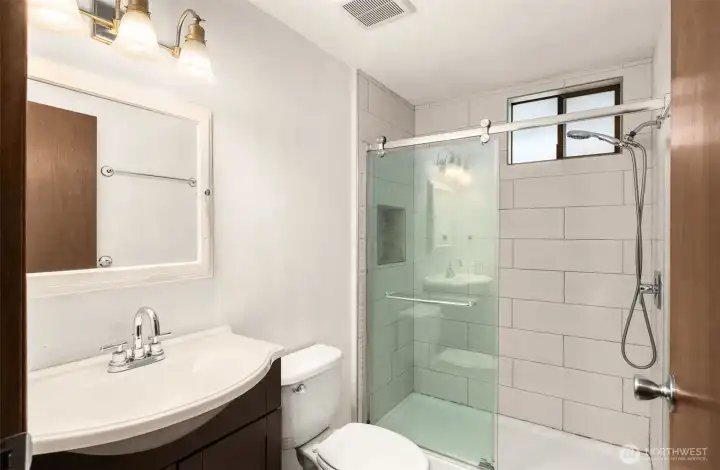 Stylishly updated upstairs bathroom featuring a refreshed shower and new ceramic tile flooring.