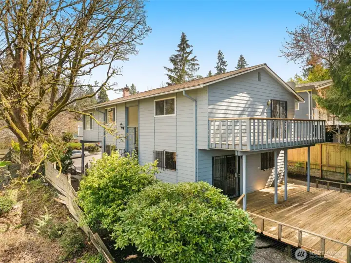 Rear view highlights the central entry, an upper balcony, and a spacious back deck—offering multiple outdoor living areas perfect for relaxing or entertaining.