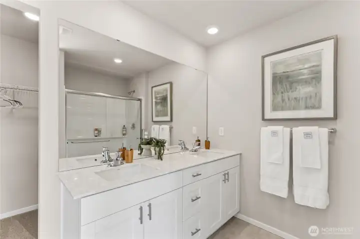 The primary bath has double vanity under mount sinks, quartz countertops and luxury vinyl flooring. Pictures are for representation only colors and options will vary.