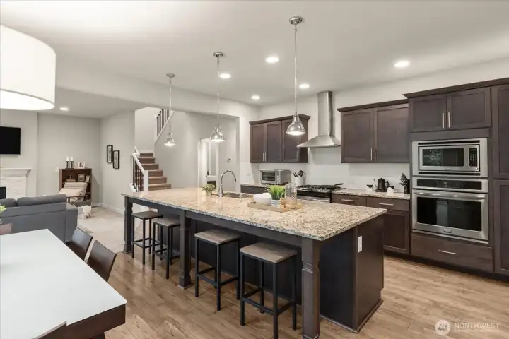True chefs kitchen with granite counters and double ovens