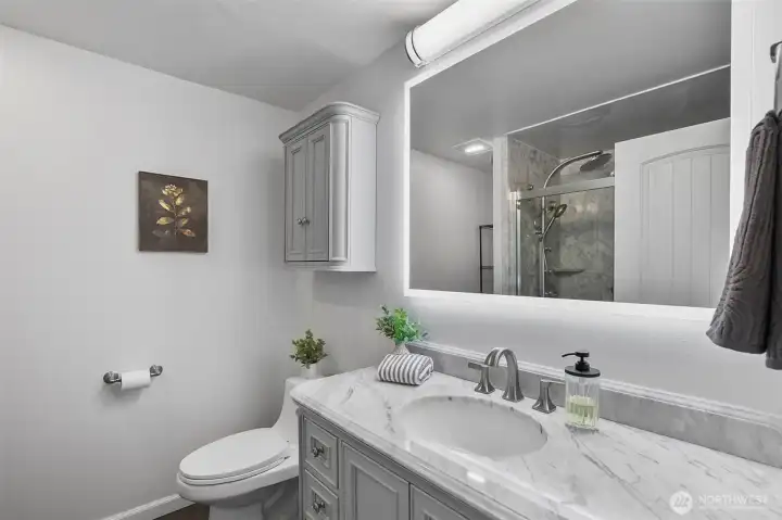 Primary bath features a walk-in shower, LED lighting, fresh paint, and beautiful new cabinetry.