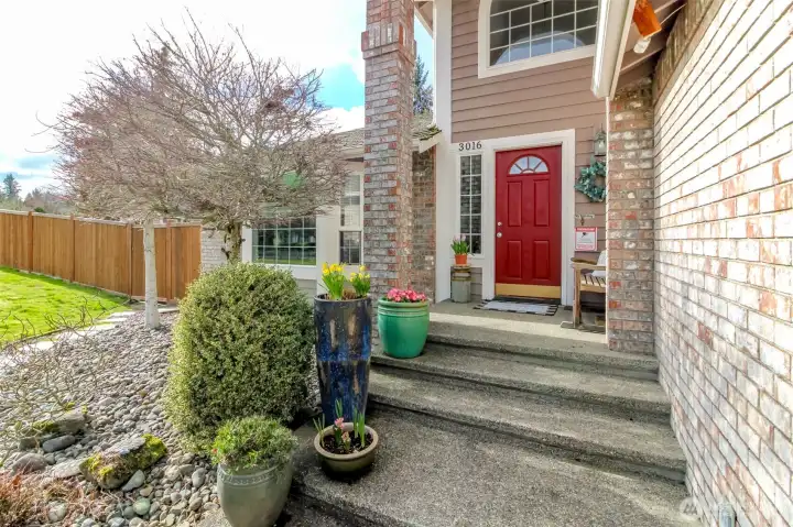 Beautiful timeless brick entry with brick-wrapped columns, large windows, and a welcoming covered porch.