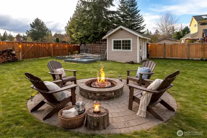 The backyard features a large fire pit that   invites cozy evening under the stars. Surrounding seating makes it perfect for gatherings, storytelling and warm memories. Nearby, a charming elevated garden area adds color, with raised planter beds. The backyard also includes a storage shed, providing practical space for tools, outdoor gear, and yard maintenance. The overall layout feels inviting and well designed for relaxing outdoors  Virtually Staged