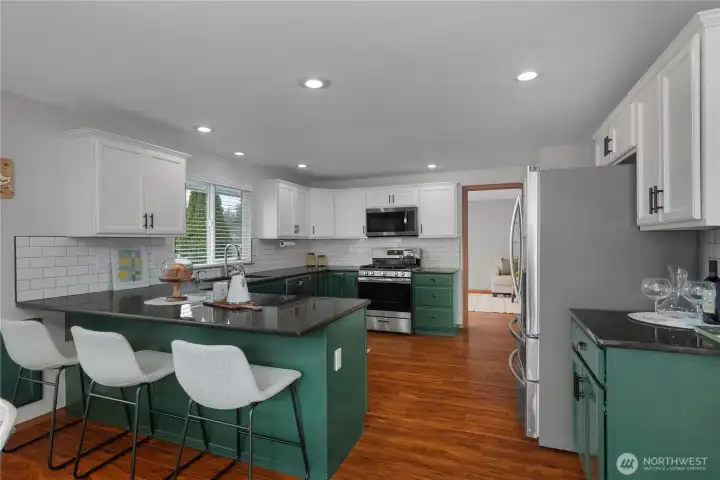 Large kitchen with granite counter tops & subway tile back splash.  Doorway headed into additional living room.