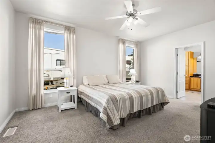 Primary suite showing california king size bed.  Ceiling fan, walk in closet and 5 piece ensuite with soaking tub and more views of the mountains.