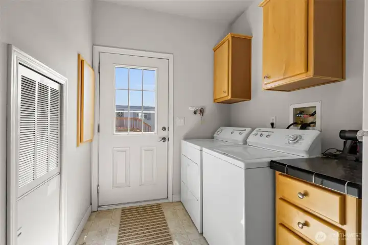 Utility room with extra refrigerator, washer and dryer conveys.  Door leading out to the deck.