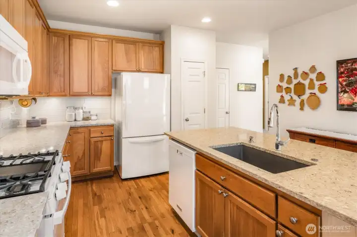 Bright, modern kitchen featuring quartz countertops, stylish backsplash, Blanco sink, and newer appliances (including 2023 range).