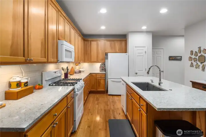 Bright, modern kitchen featuring quartz countertops, stylish backsplash, Blanco sink, and newer appliances (including 2023 range).