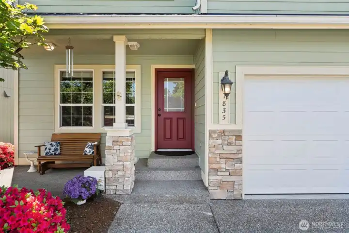 Cozy covered front porch with seating and beautiful landscaped views