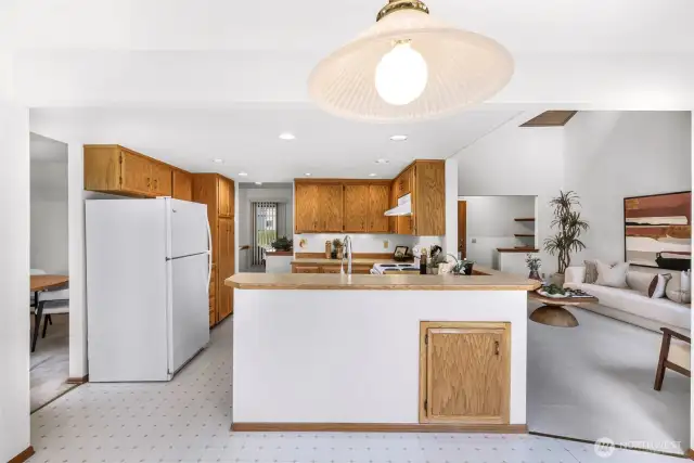 View from the kitchen highlights its seamless connection to the dining space and expansive windows beyond. Neutral flooring and cabinetry provide a timeless backdrop for everyday living.