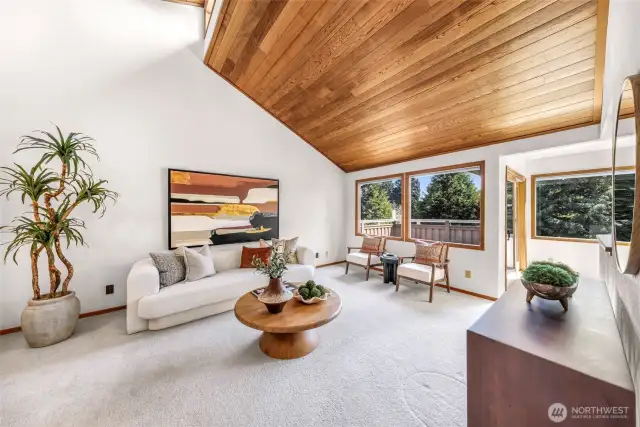 The living room opens to large windows framing treetop views and a glimpse of the nearby deck. Light pours in, accentuating the clean lines and thoughtful design.
