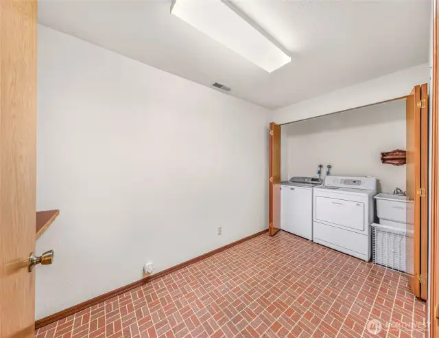 Dedicated laundry room with washer, dryer, utility sink, and storage space. Tiled floor ensures durability in this high-use area.