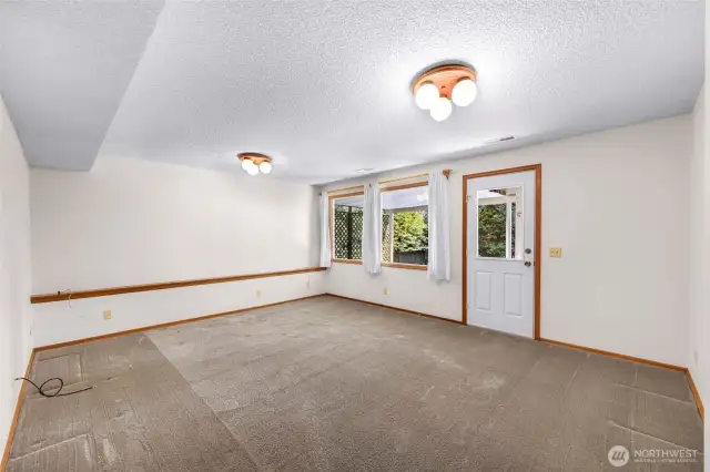 The lower-level bonus room offers spacious dimensions, closet storage, and corridor access, with a flexible layout that suits a variety of lifestyle needs. Connected to the laundry area, this open-concept space features wide carpeted floors, bright windows, and easy access to utility areas and lower bedrooms—making it ideal for recreation, hobbies, or entertainment. A private entrance to the outside adds convenience and versatility, enhancing the room’s potential as a separate living area or creative retreat.