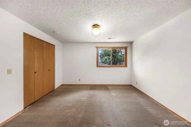 A lower-level bedroom offers a quiet retreat with a spacious layout, double-door closet, and garden-facing window for tranquil views.