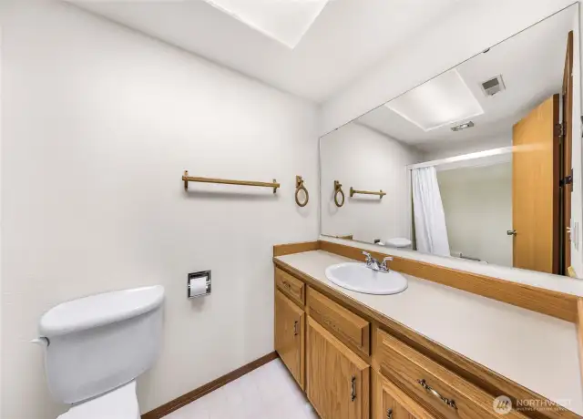 Another angle of the lower-level bathroom reveals a toilet and shower/tub combination, offering full amenities in this secondary suite-style bath.