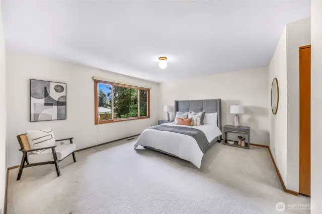 The primary bedroom is spacious and tranquil, featuring neutral tones, a large window, and ample space for furnishings. A relaxing retreat with ensuite access.