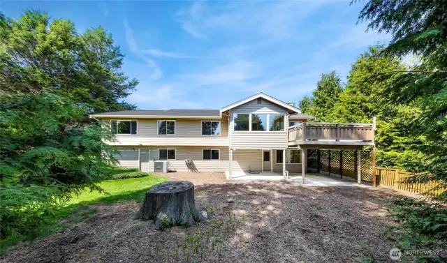 Rear elevation reveals a fully fenced yard and double-level design, including a covered patio and large deck above—ideal for entertaining and privacy.