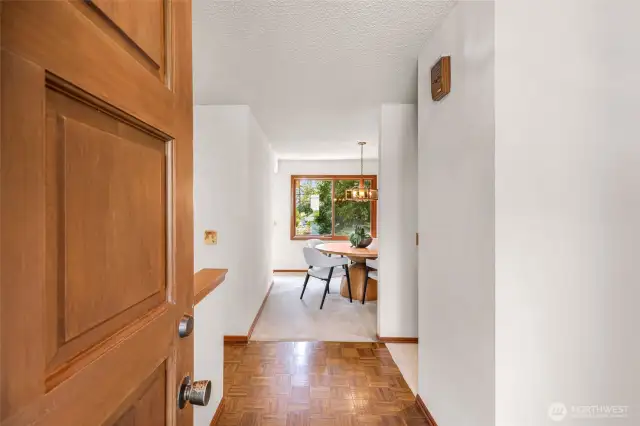 A hallway connects the entryway and main living space, featuring parquet wood flooring and neutral walls. Efficient design enhances flow throughout the upper level.