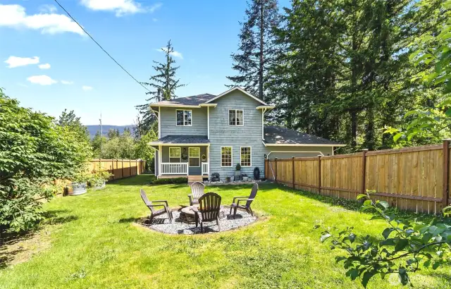 Closer view of fenced front yard with fire pit.