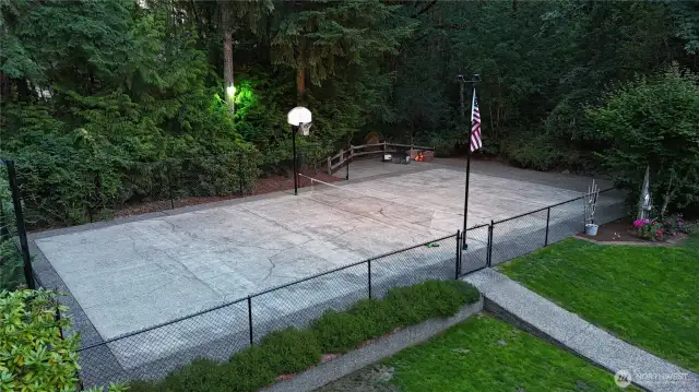 Drone Shot Sports Court, w/ Fire Pit right above the rippling year round creed in the greenbelt beyond.