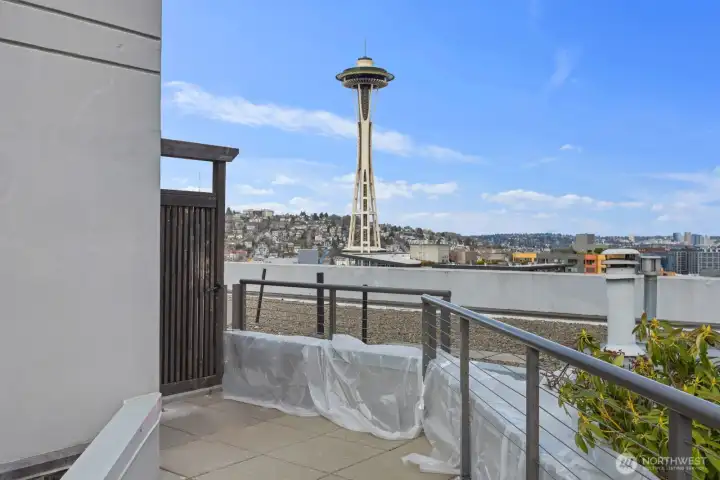 Seattle rooftop deck with Space Needle view, outdoor seating area, and elevated perspective overlooking surrounding Queen Anne hillside and city skyline.