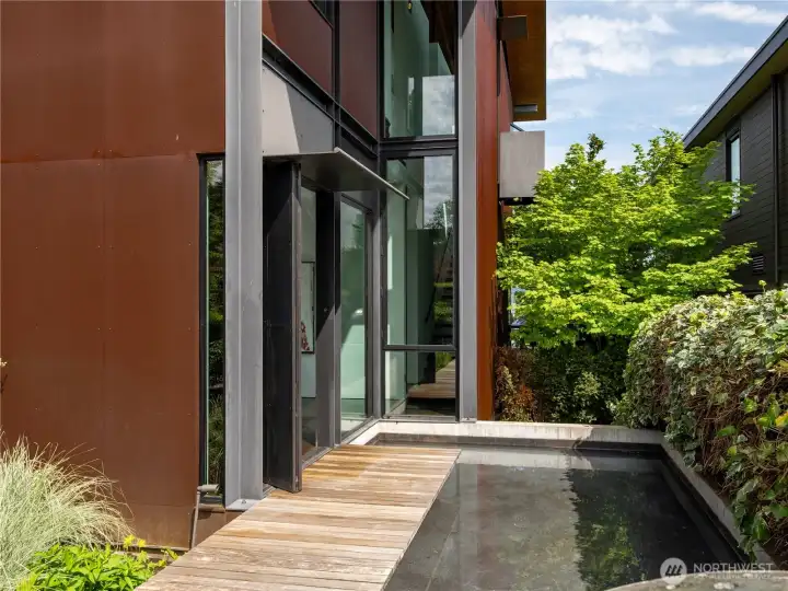 Private entry walkway "floats" over the water feature with art installation by Brandon Zebold.