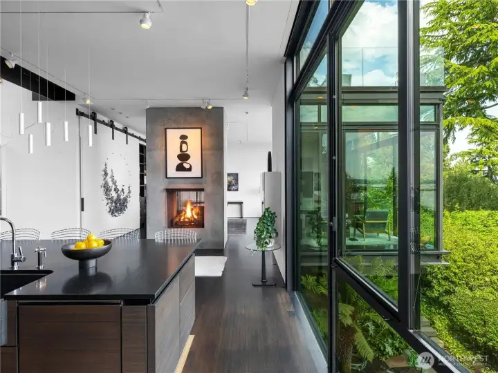 Concrete and steel fireplace creates an artistic and functional separation between the kitchen and dining room.