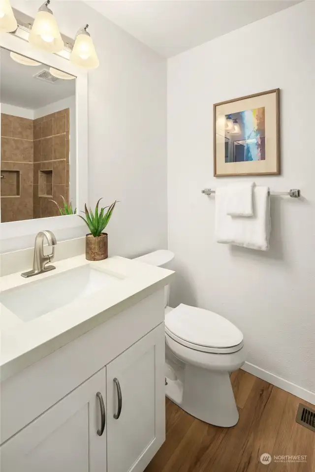 The remodeled bathroom has a new cabinet, quartz counter, sink, faucet, mirror and lighting.