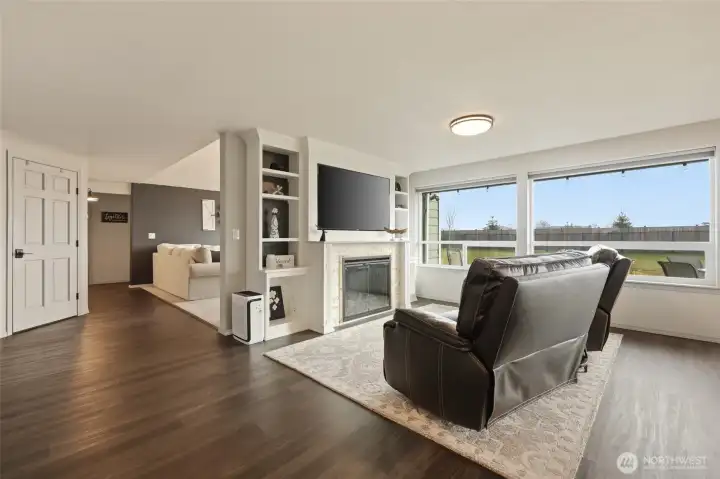 Open floorplan has this beautiful space off the kitchen, with stone surround and classy built-ins, and two picture windows to maintain the view...