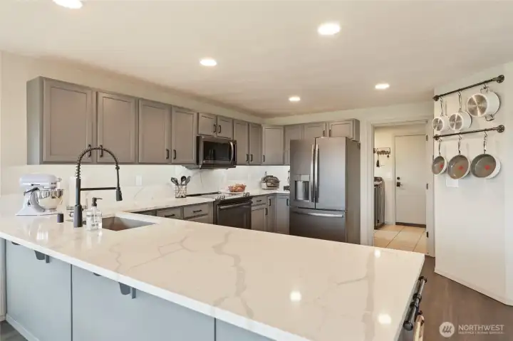 Captivating kitchen boasts sublime quartz counters, recessed lighting, and appliance suite--who wouldn't enjoy spending time here??