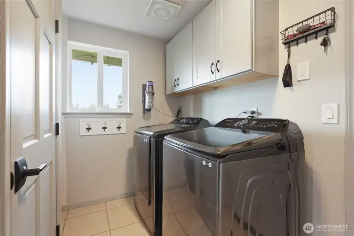 Located off the kitchen and on the way to the garage, this well-lit laundry room offers tile floors, and storage in both wall cabinets and additional pantry/closet!