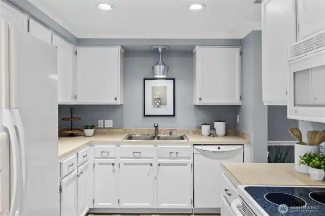 Kitchen has white cabinets and can lights