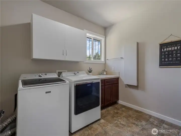 Upper level laundry room with storage cabinets, utility sink and built-in ironing board.