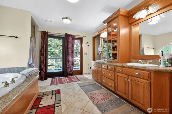 The master suite is complemented by a spacious spa-inspired bathroom featuring rich wood cabinetry, granite countertops, an oversized linen closet, a jetted soaking tub, and a separate shower.