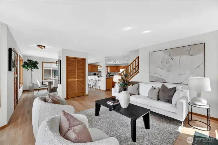 Bright, welcoming entry with warm hardwood floors, open sightlines, and seamless flow connecting the living, dining, and kitchen spaces.