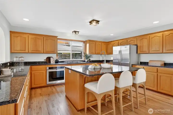 Bright and expansive chef’s kitchen featuring generous counter space, stainless appliances, abundant cabinetry, and a large island perfect for gathering.