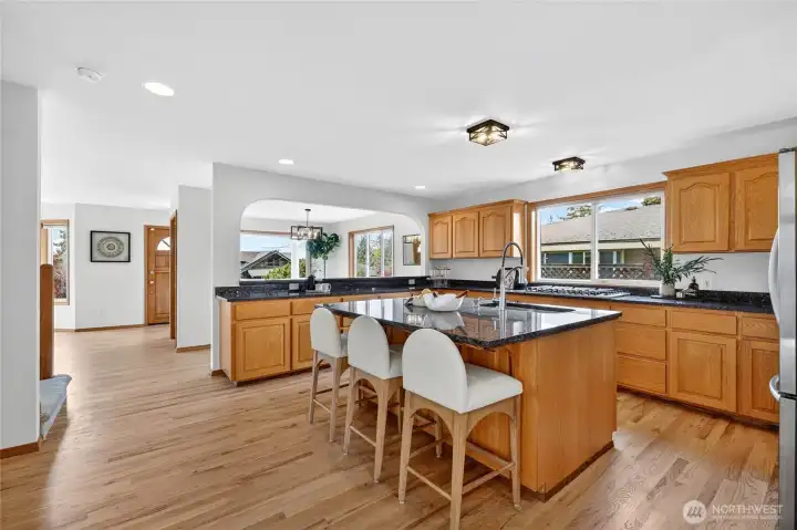 Expansive open-concept kitchen with oversized island seating, abundant cabinetry, and seamless flow into the home’s bright gathering spaces.