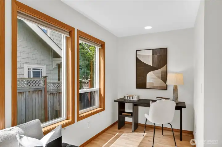 Bright flex space perfect for a home office or reading nook, featuring oversized windows, warm natural light, and peaceful privacy.