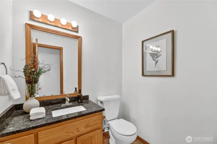 Stylish main-level powder room with granite counters, warm wood cabinetry, and clean timeless finishes.